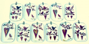 Fused-glass Valentine's Day decorations of birds and hearts hanging from twigs